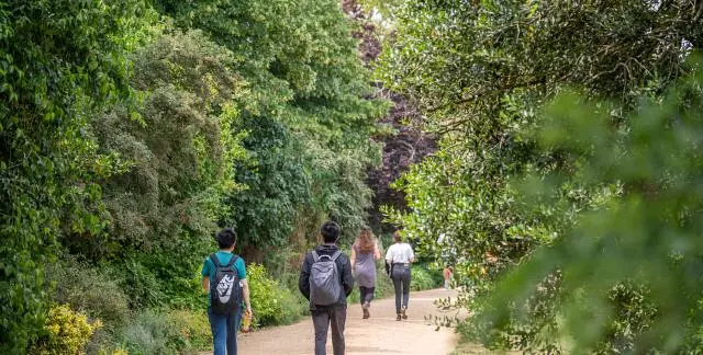 People walking along a tree-lined path in University Parks
